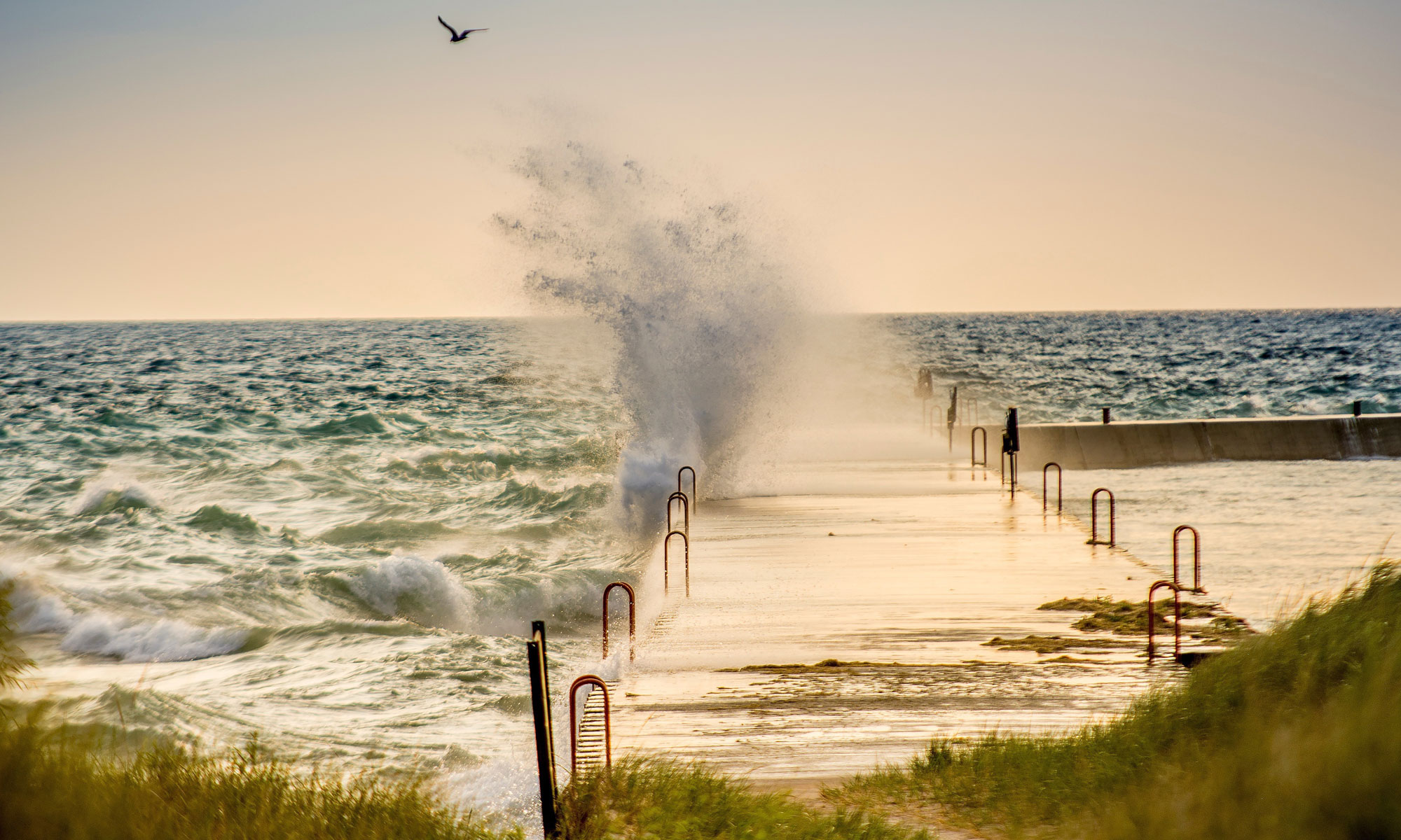 Eine Brandungswelle bricht sich an einem Steg; Fotograf: StockSnap, pixabay.com