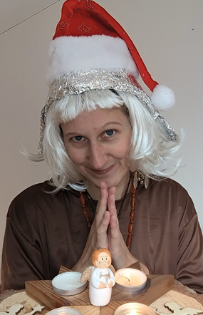 Frau Eso Terica als Teil des Inneren Teams sitzt mit Nikolausmütze hinter einem Kerzenlicht und lächelt in die Kamera