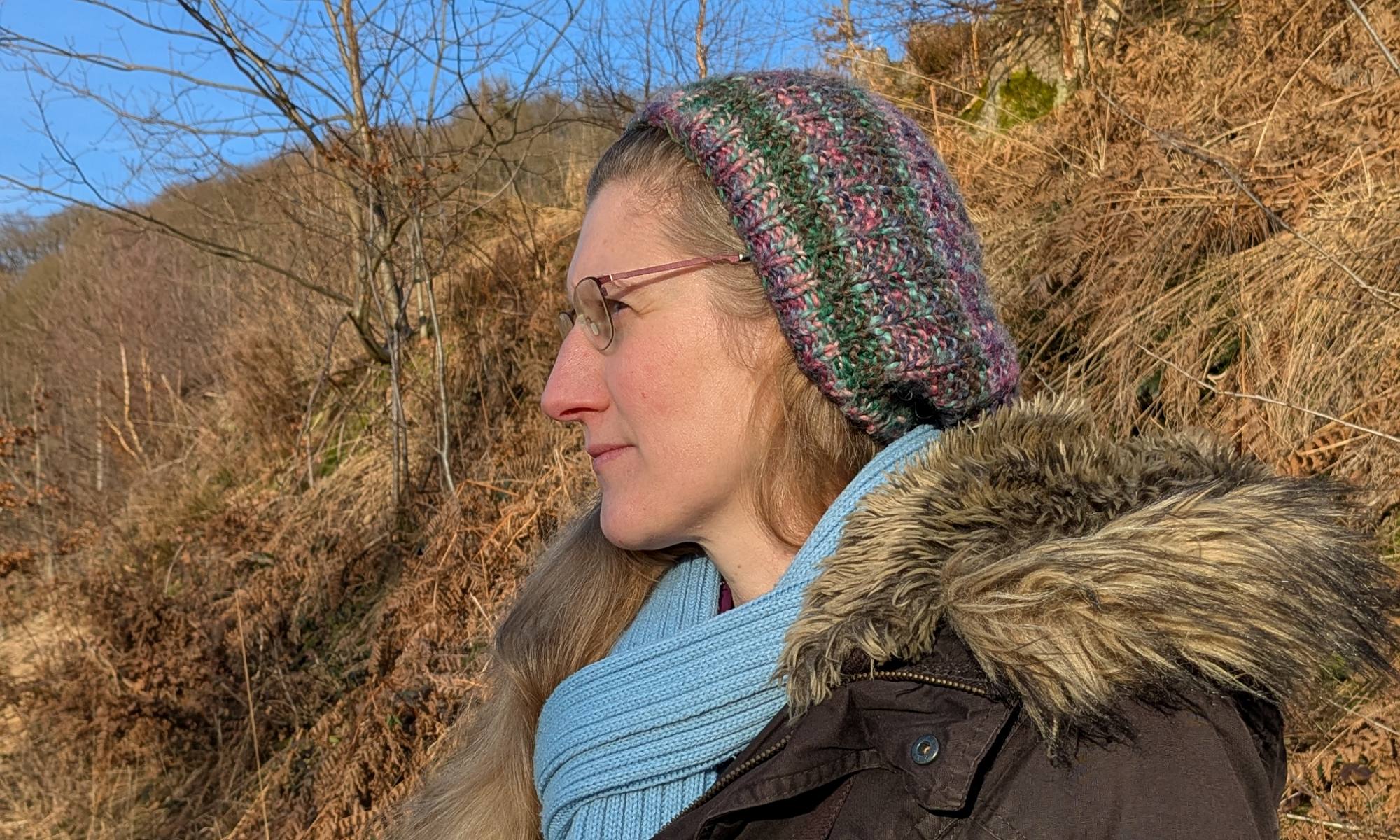 Dorothee steht auf einem Waldweg im Sonnenschein und blickt in die Ferne