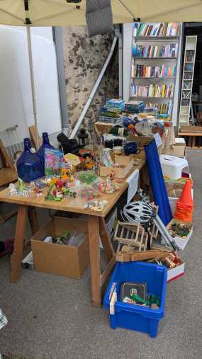 Der Flohmarktstand vor der Garage mit Spielzeug, Hausrat und einem Regal voller Bücher