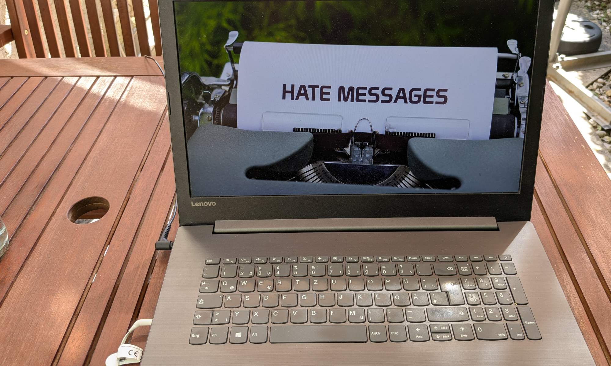 Auf einem Laptopbildschirm ist das Bild einer Schreibmaschine zu sehen, die ein Papier mit dem Wort Hate Messages eingespannt hat