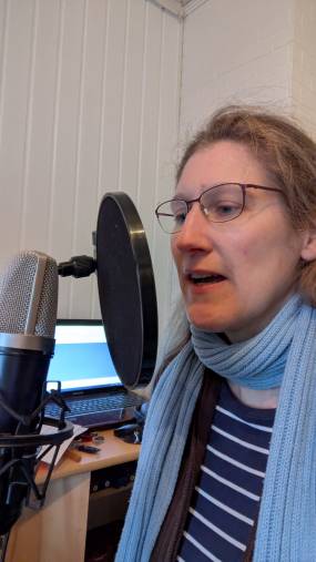 Dorothee sitzt vor einem Mikrofon und macht eine Aufnahme