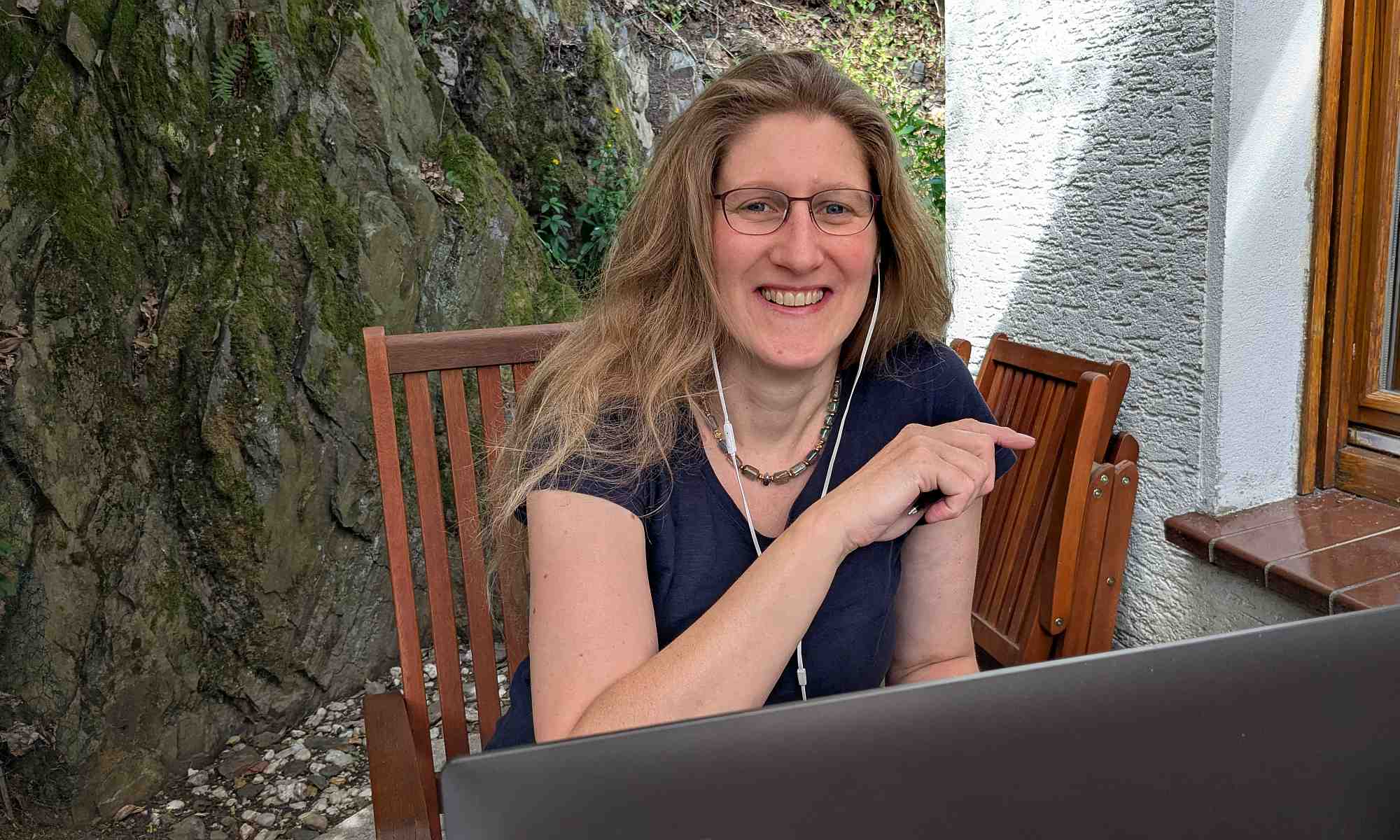 Dorothee sitzt sichtbar auf der Terrasse ihrem Laptop, zufrieden über ihren neuen Blogartikel