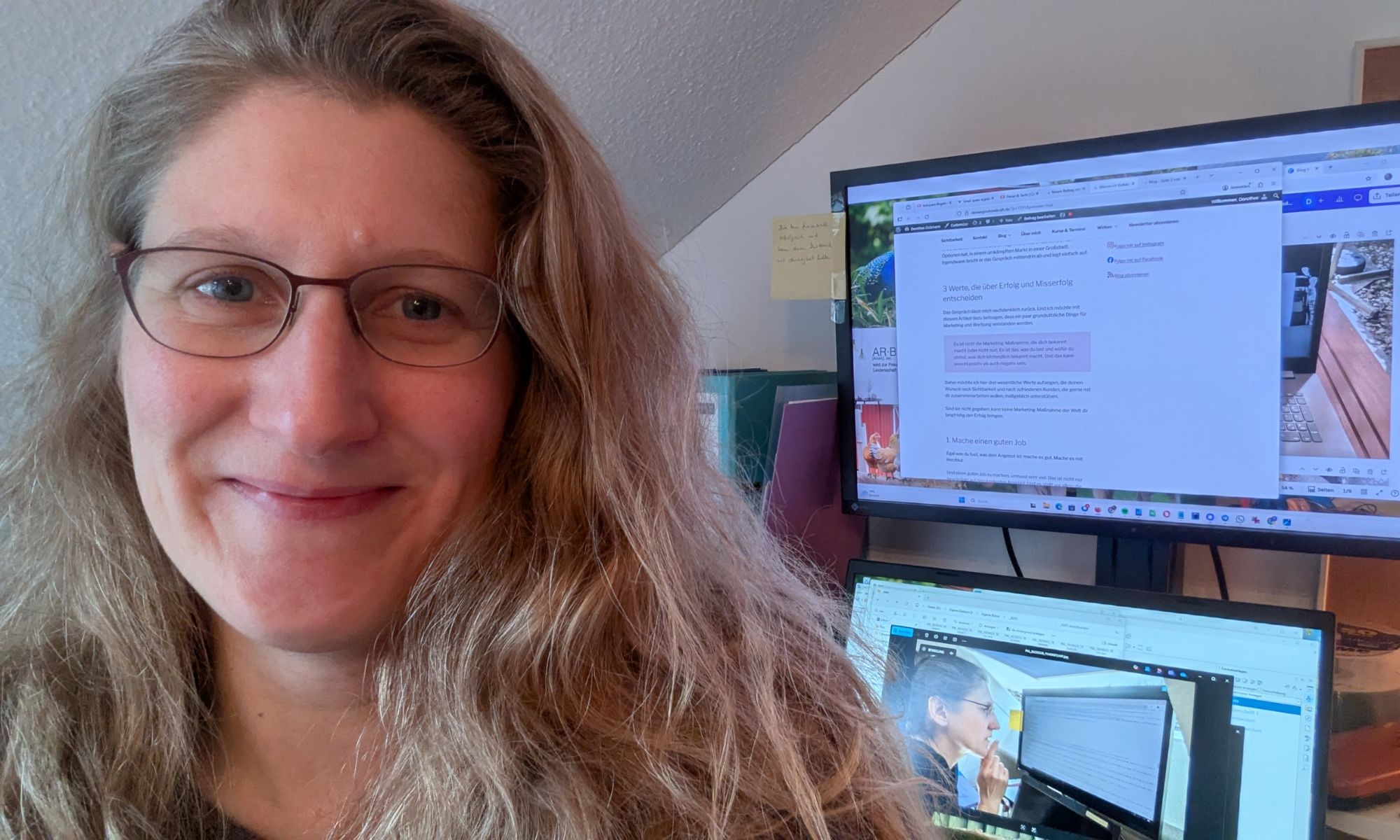 Dorothee lächelt in die Kamera, im Hintergrund steht ein Laptop und Bildschirm