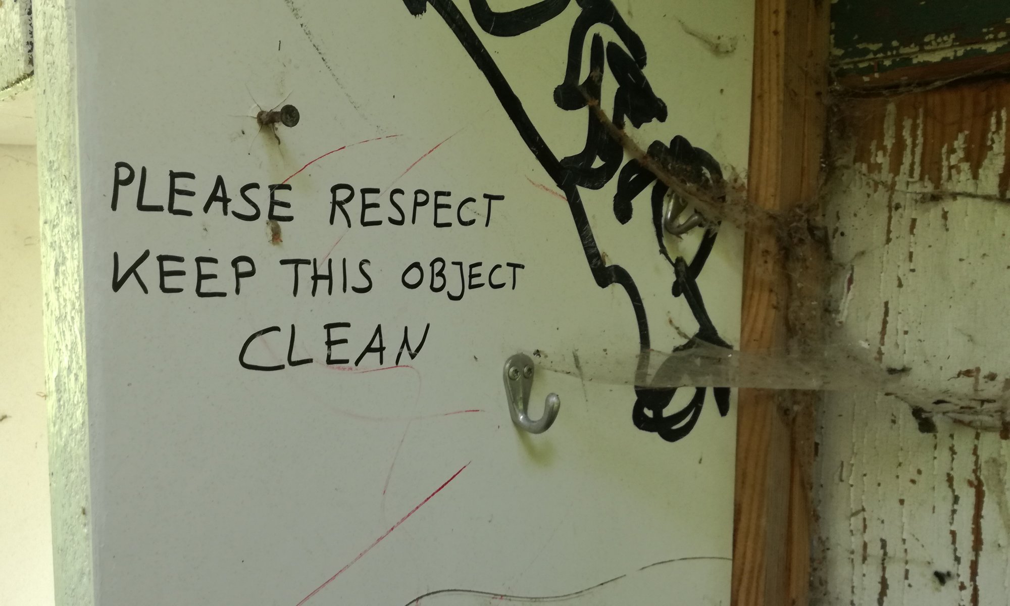 Eine Wand mit Spinnenweben und Staub verdreckt mit der Aufschrift Please respect keep this object clean
