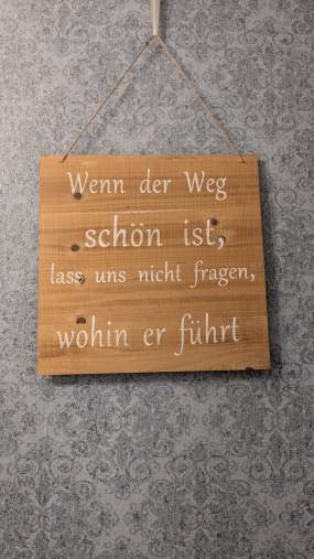 Ein Schild mit einem Spruch hängt an der Wand