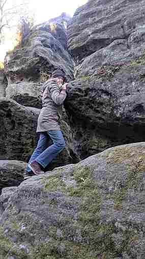 Dorothee stemmt spaßeshalber gegen einen großen Felsen im Langhennersdorfer Felsenlabyrinth