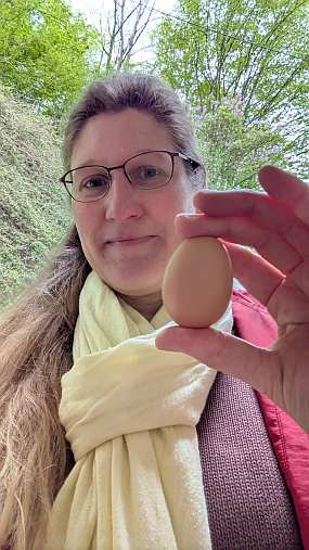 Dorothee hält glücklich das erste Ei von den eigenen Hühnern in die Kamera